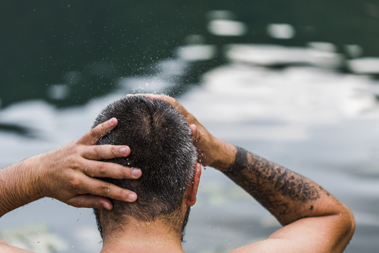rear-view-man-hair Bild zeigt Mann im Wasser mit nassen Haaren im Winter, der über eine Haartransplantation nachdenkt